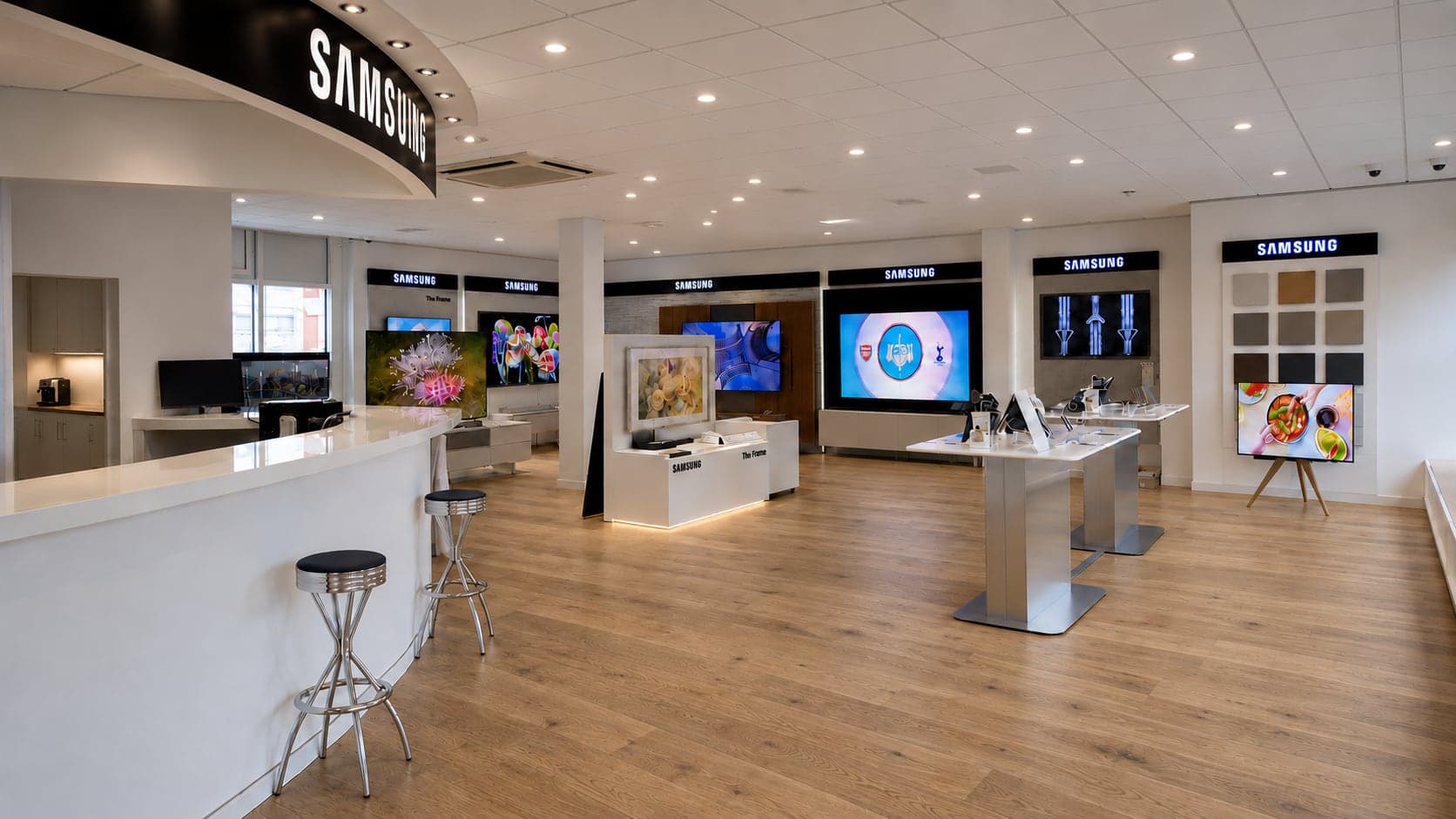 Samsung-Welt im Showroom im Überblick: Empfangstheke, The-Frame-Tisch und TV-Wände mit laufenden Modellen