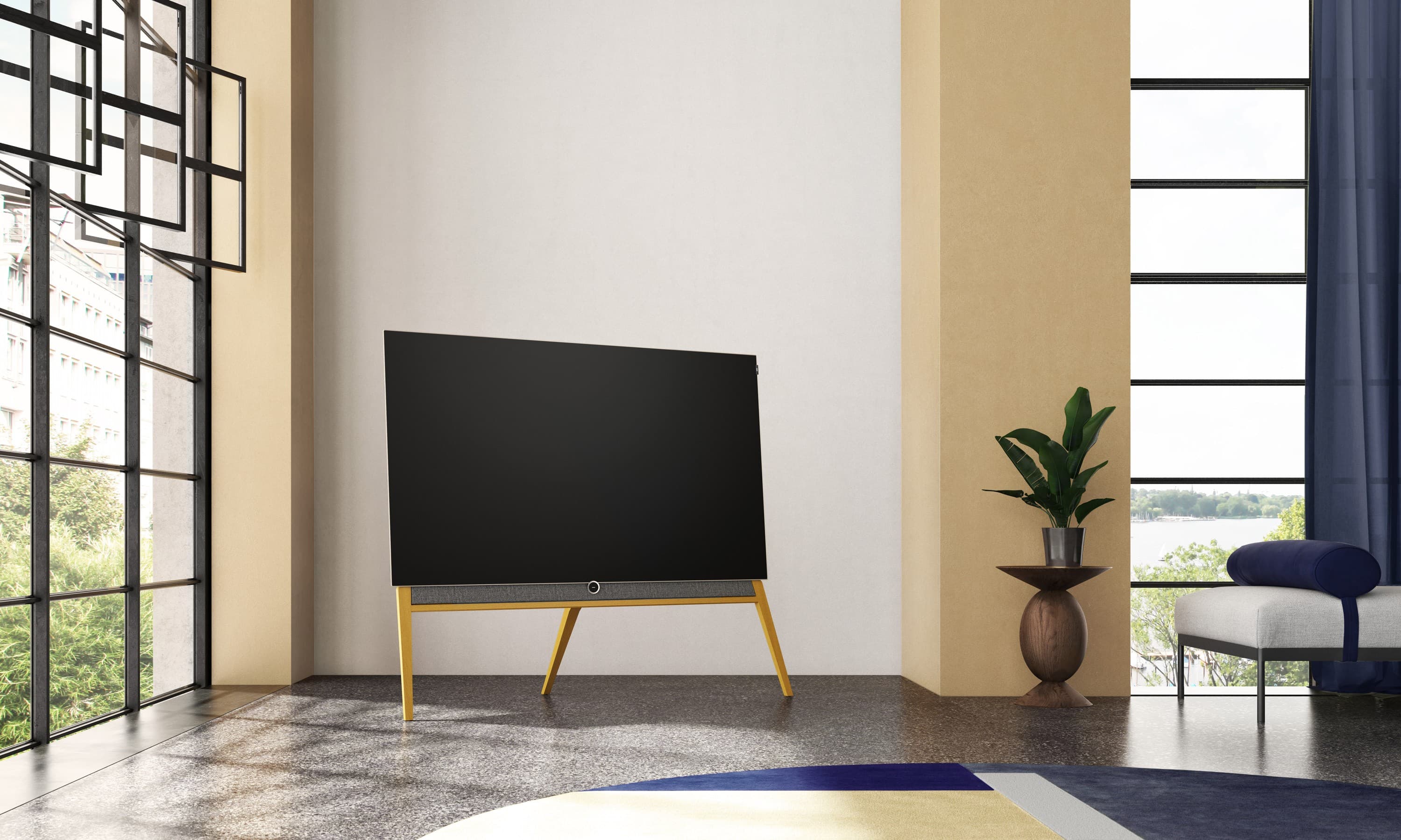 Frei stehender Fernseher auf schlanken Holzfüssen in einem ruhigen, hellen Wohnraum (Herstellerbild Loewe)